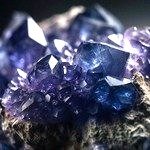 The extreme close-up explores the enigmatic surface of an iolite. Shimmering blues and purples play across its surface, like a night sky filled with distant galaxies.